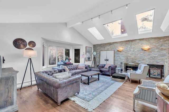 living room with a skylight, baseboard heating, a stone fireplace, high vaulted ceiling, and hardwood / wood-style flooring