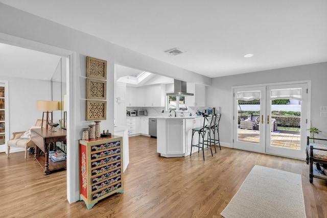 kitchen featuring kitchen peninsula, french doors, island range hood, dishwasher, and white cabinets