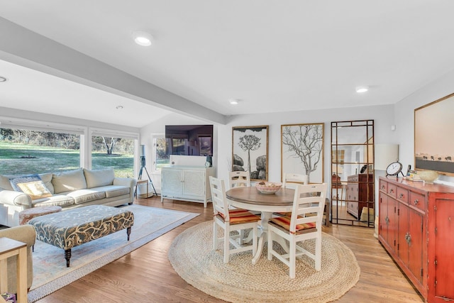 dining room featuring light wood-type flooring and vaulted ceiling