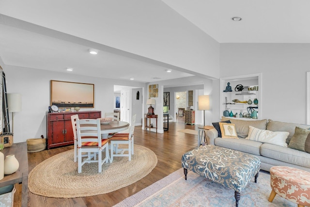 living room featuring built in shelves, dark hardwood / wood-style floors, and vaulted ceiling