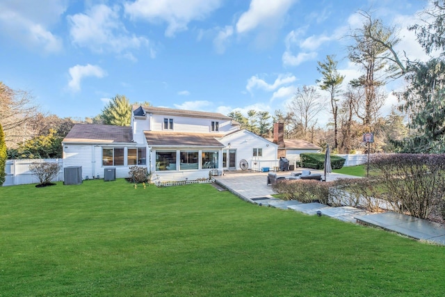 rear view of property with central AC unit, a sunroom, a patio area, and a yard