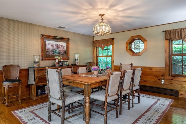 dining area with hardwood / wood-style floors, a baseboard heating unit, and an inviting chandelier