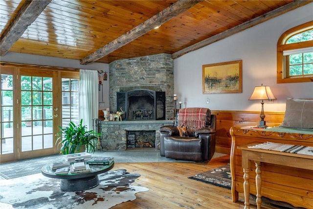 living room featuring wooden ceiling, hardwood / wood-style floors, vaulted ceiling with beams, and a stone fireplace