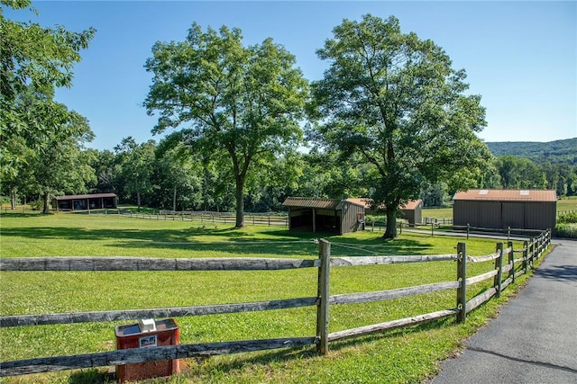 surrounding community with an outbuilding, a rural view, and a lawn