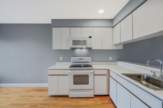 kitchen with white appliances, light hardwood / wood-style flooring, white cabinetry, and sink