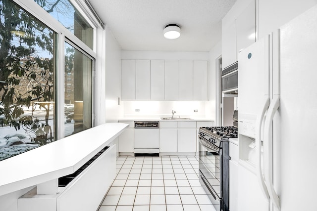 kitchen featuring white cabinetry, sink, white appliances, and a textured ceiling