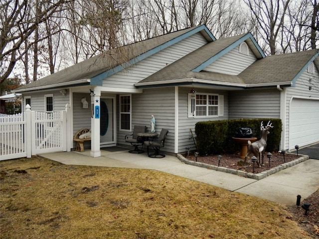 ranch-style house featuring a garage, driveway, a shingled roof, and fence