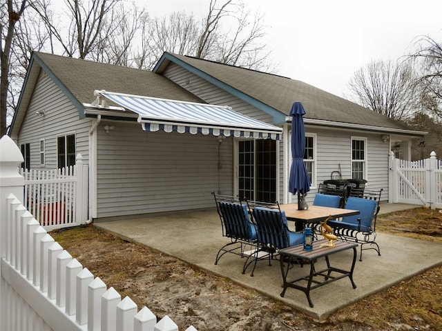 rear view of house featuring a patio area, a shingled roof, a gate, and fence