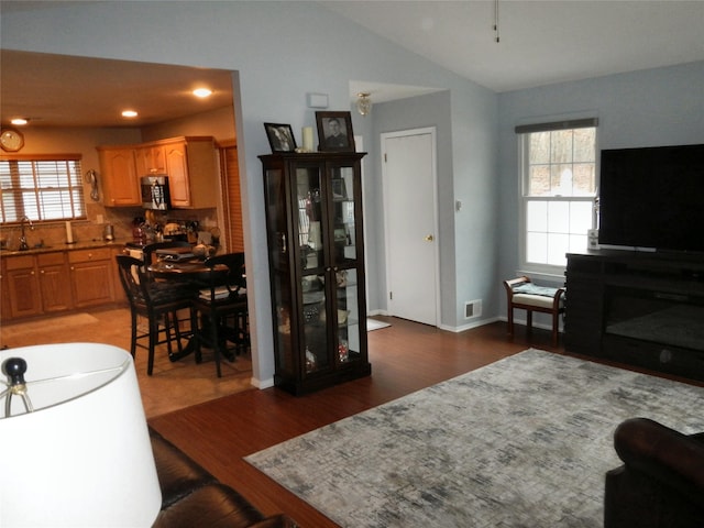 living room with lofted ceiling, baseboards, visible vents, and wood finished floors