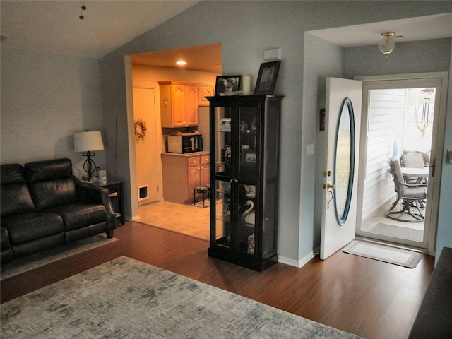 living area with lofted ceiling, visible vents, baseboards, and wood finished floors