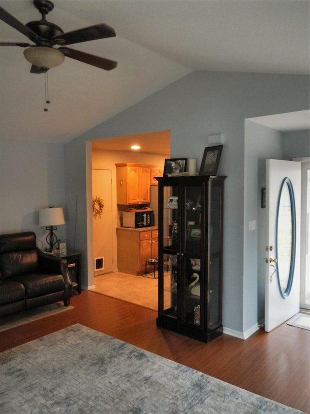 living area with a ceiling fan, lofted ceiling, and wood finished floors