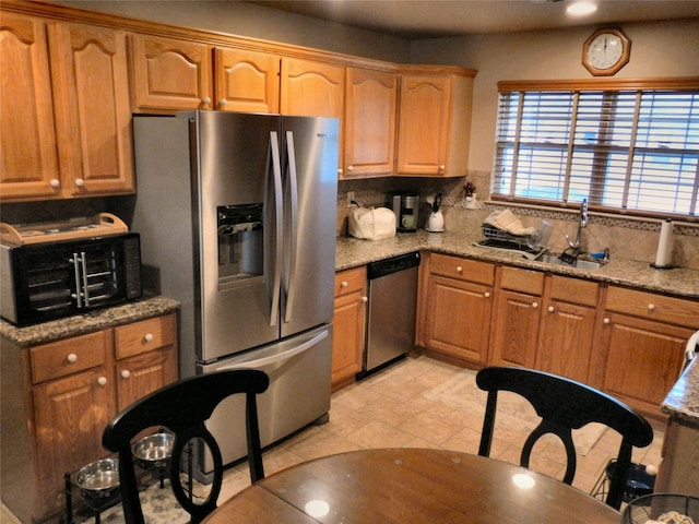 kitchen featuring a toaster, light stone counters, backsplash, stainless steel appliances, and a sink