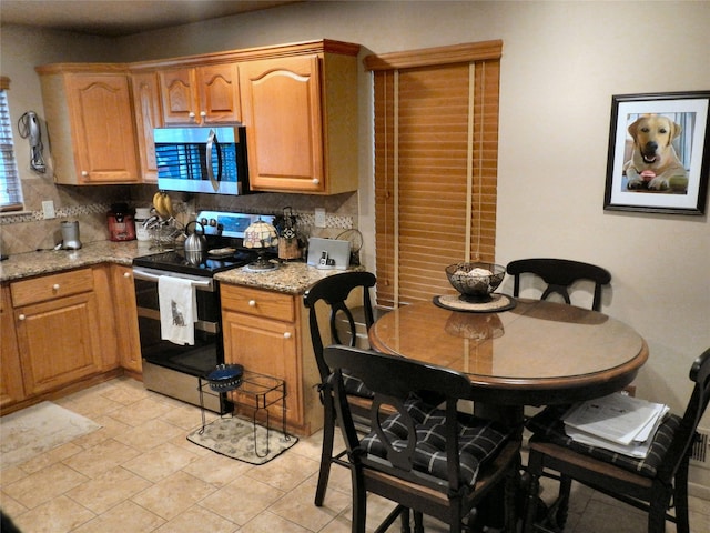 kitchen with stainless steel appliances, backsplash, and light stone countertops