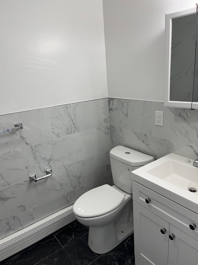 bathroom featuring vanity, toilet, and tile walls