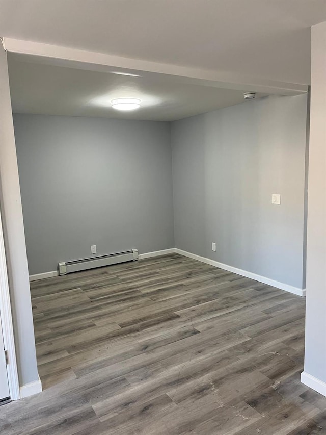 unfurnished room with dark wood-type flooring and a baseboard heating unit