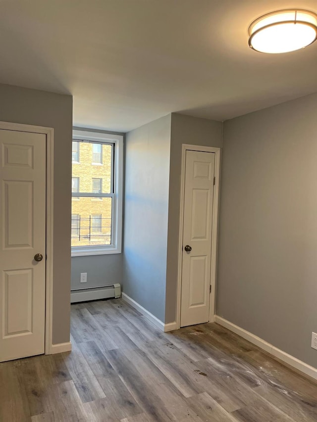 unfurnished room featuring hardwood / wood-style floors and baseboard heating