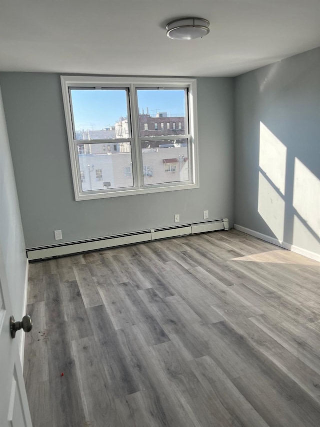 unfurnished room with light hardwood / wood-style floors and a baseboard heating unit