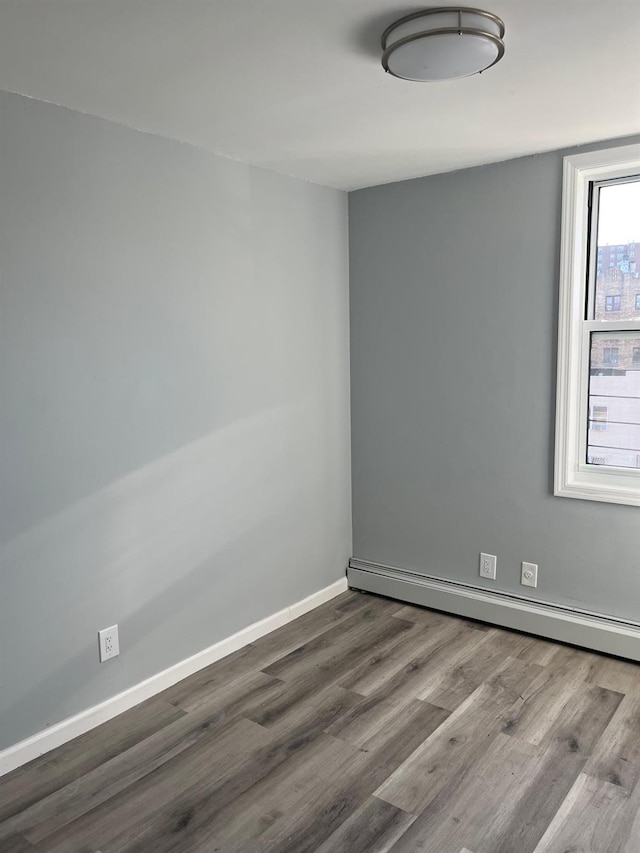 empty room with baseboard heating and wood-type flooring