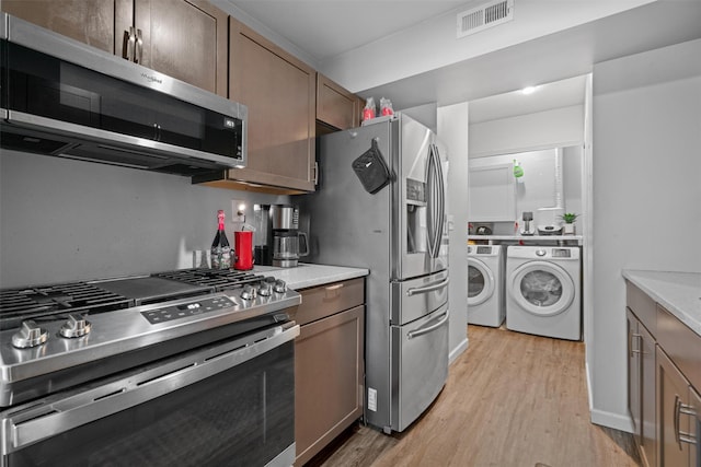 kitchen with light hardwood / wood-style flooring, stainless steel appliances, and independent washer and dryer