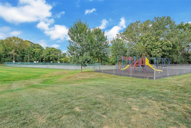 view of playground with tennis court and a yard