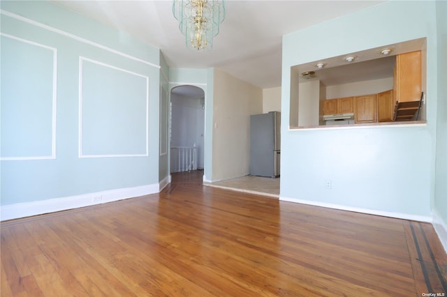 unfurnished living room featuring wood-type flooring and a notable chandelier