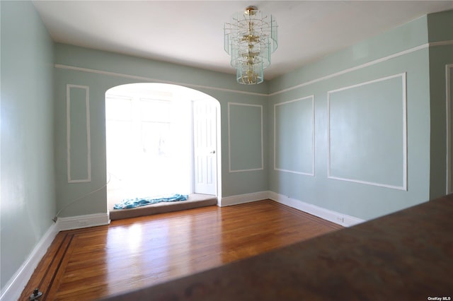 unfurnished room featuring wood-type flooring and a chandelier