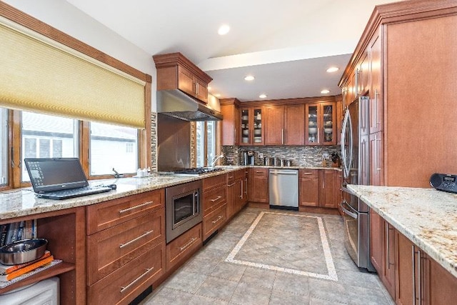 kitchen with decorative backsplash, stainless steel appliances, and light stone counters