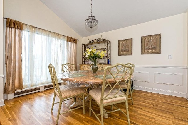 dining area featuring hardwood / wood-style floors, a baseboard radiator, lofted ceiling, and a notable chandelier