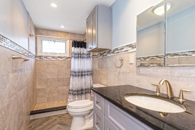 bathroom featuring vanity, toilet, tile walls, and walk in shower