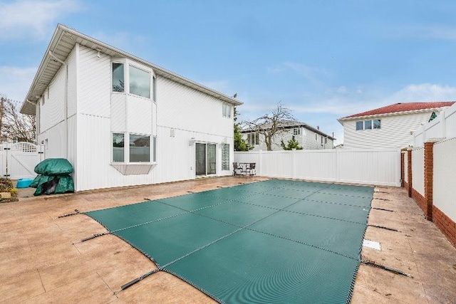 rear view of property featuring a patio area and a covered pool