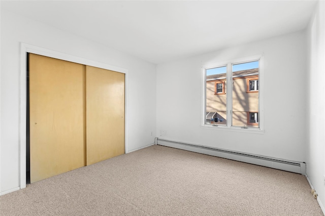 unfurnished bedroom featuring a closet, carpet, and a baseboard heating unit