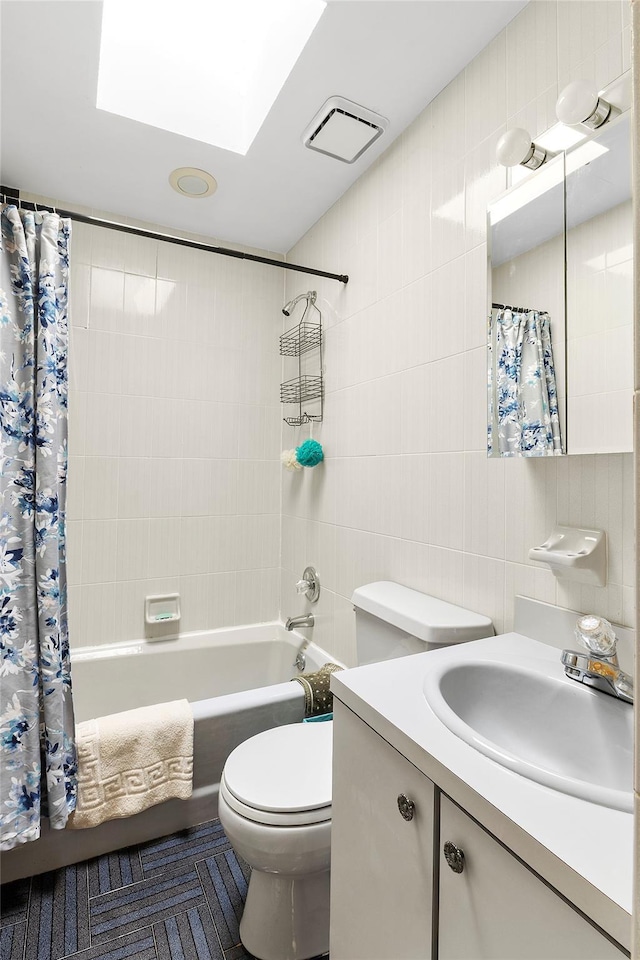 bathroom with visible vents, toilet, shower / bathtub combination with curtain, vanity, and tile walls