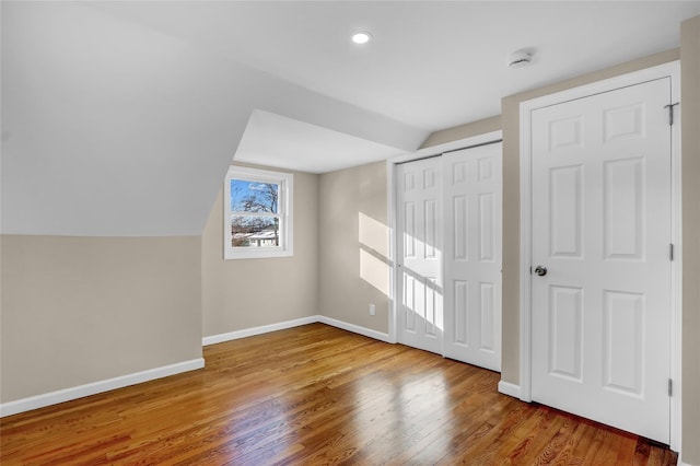 additional living space featuring wood-type flooring and vaulted ceiling