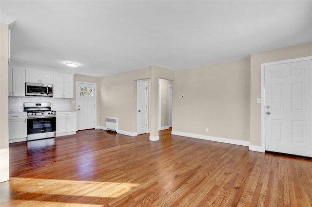 unfurnished living room featuring radiator heating unit and light wood-type flooring