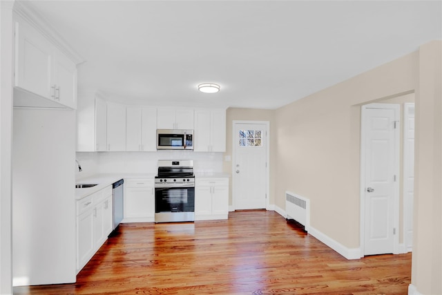 kitchen with white cabinets, appliances with stainless steel finishes, and radiator