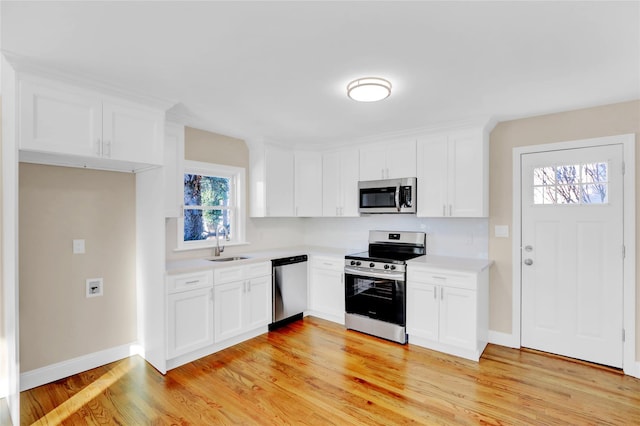 kitchen with stainless steel appliances, white cabinetry, light hardwood / wood-style floors, and sink