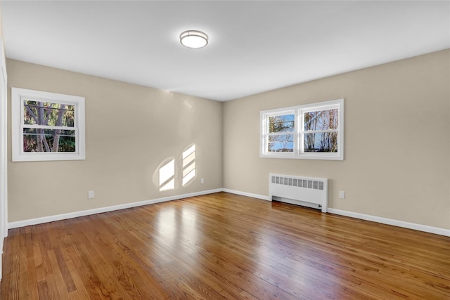 empty room with hardwood / wood-style flooring and radiator heating unit