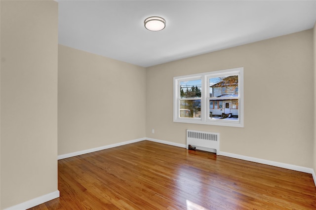 empty room featuring radiator heating unit and hardwood / wood-style floors