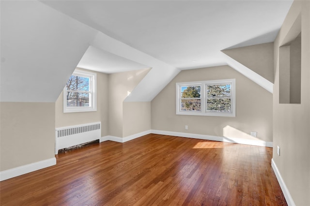 additional living space featuring hardwood / wood-style floors, radiator, and lofted ceiling