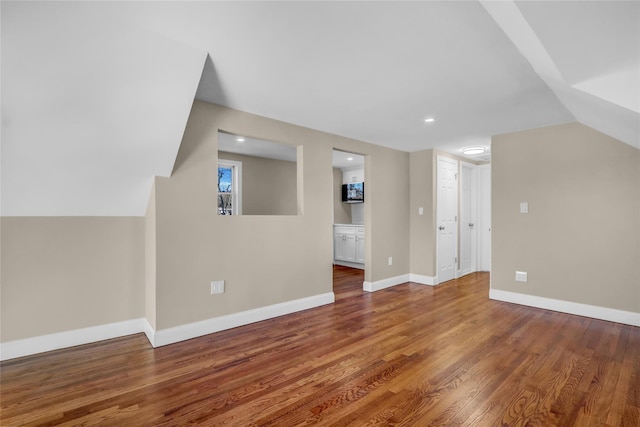 additional living space featuring wood-type flooring and vaulted ceiling