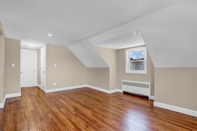 additional living space with lofted ceiling, wood-type flooring, and radiator