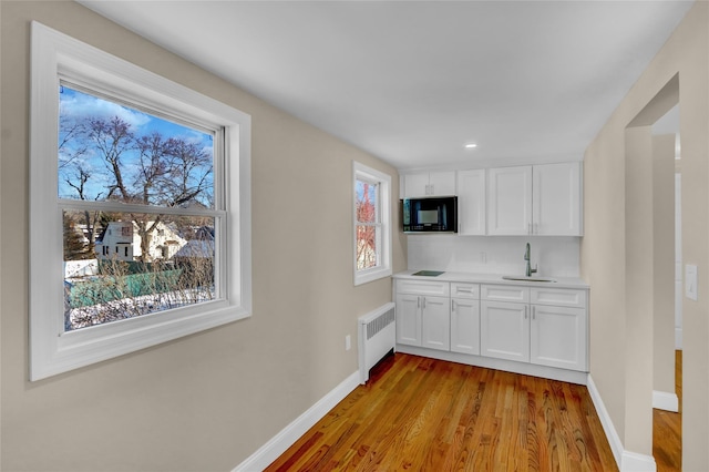 kitchen with white cabinets, a healthy amount of sunlight, sink, and radiator