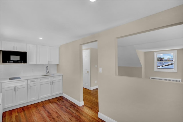 kitchen featuring white cabinets, wood-type flooring, and sink