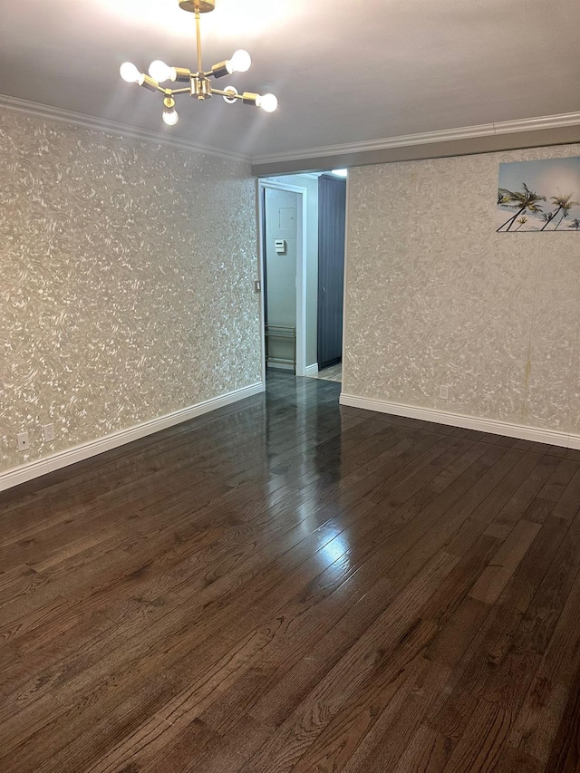 empty room with a chandelier, ornamental molding, and dark wood-type flooring