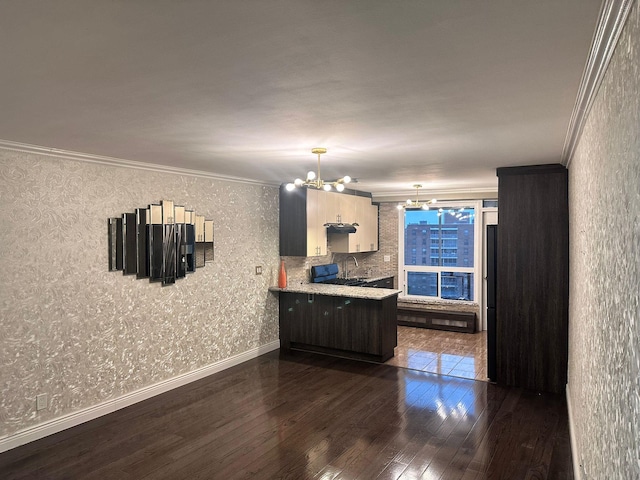 kitchen featuring pendant lighting, an inviting chandelier, dark hardwood / wood-style floors, ornamental molding, and kitchen peninsula