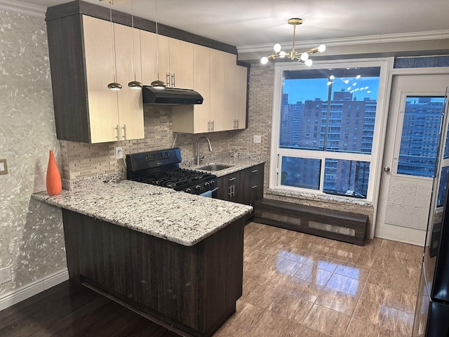 kitchen featuring light stone countertops, ornamental molding, black range with gas stovetop, sink, and a notable chandelier