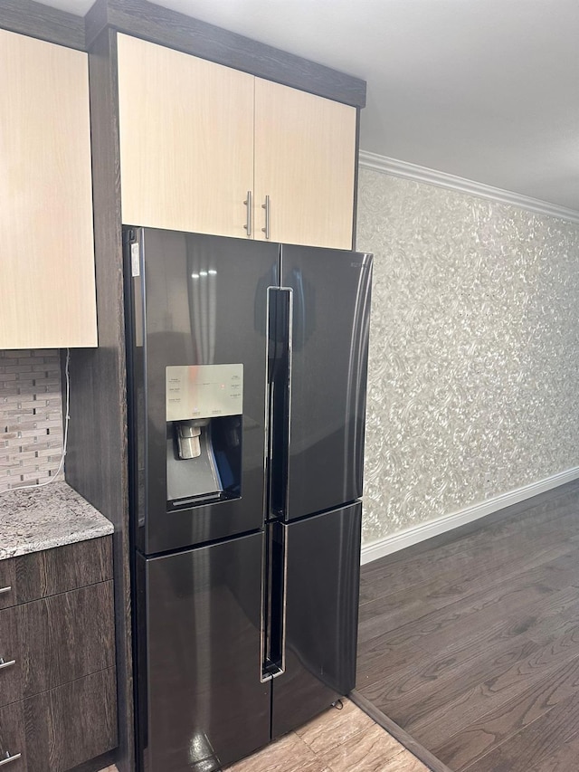 kitchen featuring light hardwood / wood-style floors, light stone counters, ornamental molding, and fridge with ice dispenser