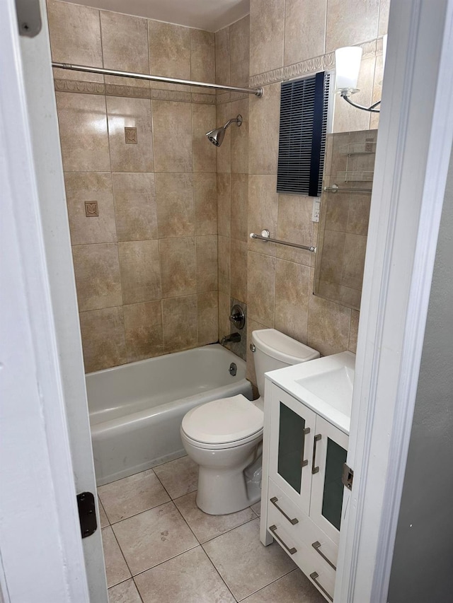 full bathroom with vanity, tile walls, tile patterned flooring, toilet, and tiled shower / bath