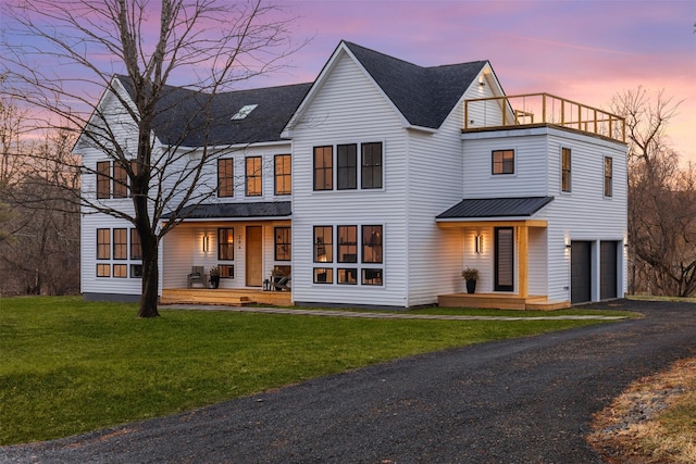 view of front of home with a lawn, a balcony, a porch, and a garage