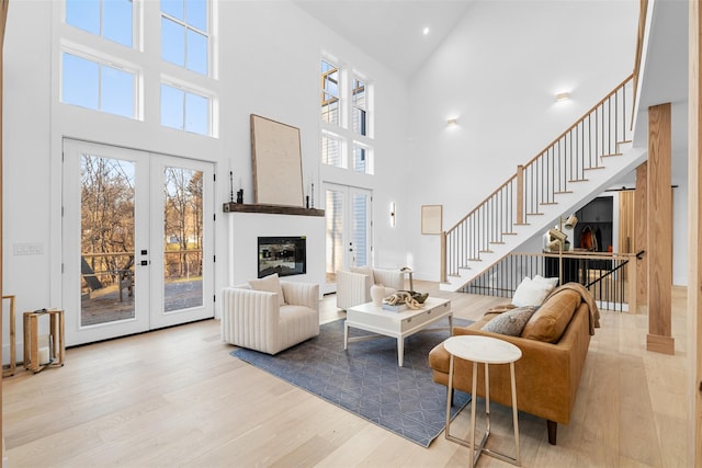 living room with a high ceiling, light hardwood / wood-style floors, and french doors